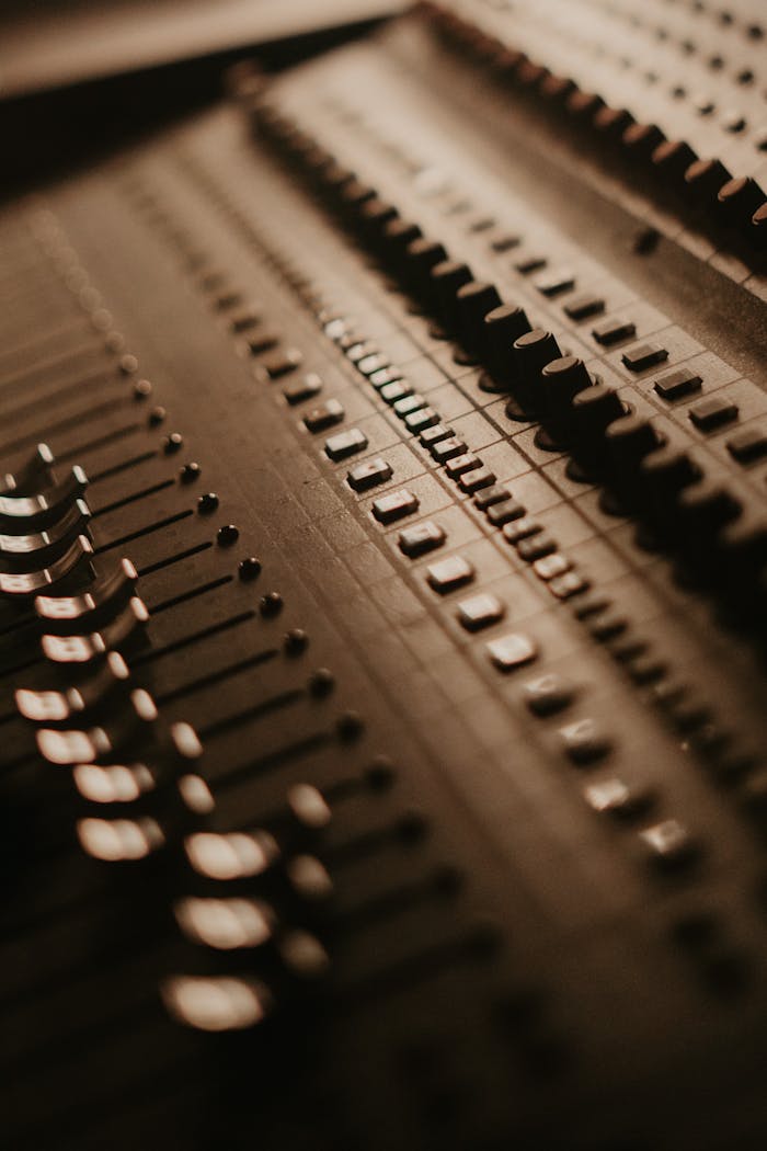 Close-up shot of a professional audio mixer with slide controls in warm lighting, showcasing analog audio technology.